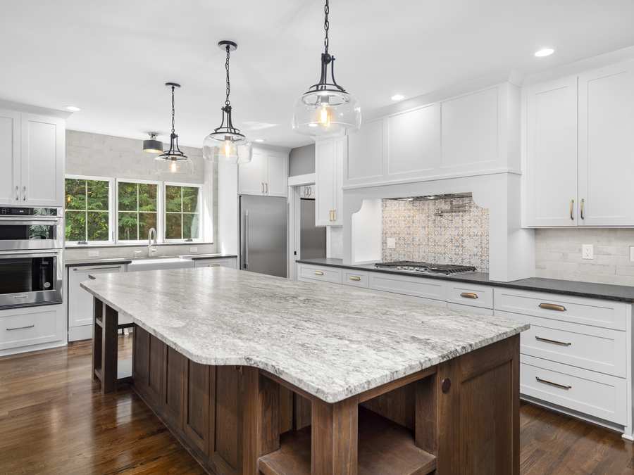 White kitchen with a granite island and glass pendants
